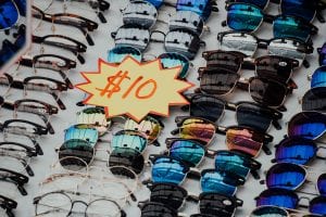 Assorted eyeglasses and sunglasses with sign reading &ldquo;$10&rdquo;; image by Chutterstock, via Unsplash.com.