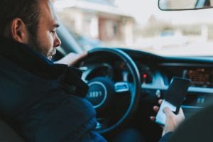 Driver using smartphone behind the wheel; image by Alexandre Boucher, via Unsplash.com.
