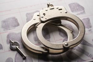 Handcuffs with key sitting on fingerprint card; image by Bill Oxford, via Unsplash.com.