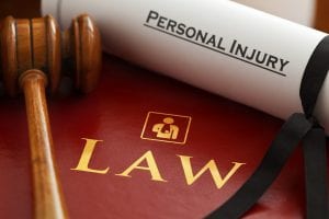 Gavel and rolled document saying &ldquo;Personal Injury&rdquo; resting atop maroon book saying &ldquo;Law.&rdquo; Image by Claimaccident, via Pixabay.com.