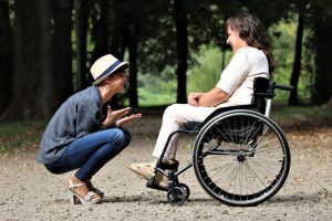 Woman seated in wheelchair facing woman in hat; image by Judita Tamo&scaron;iūnaitė, via Pexels.com.