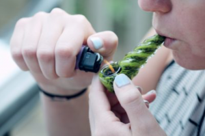 Woman lighting marijuana in pipe; image by Sharon McCutcheon via Unsplash.com.
