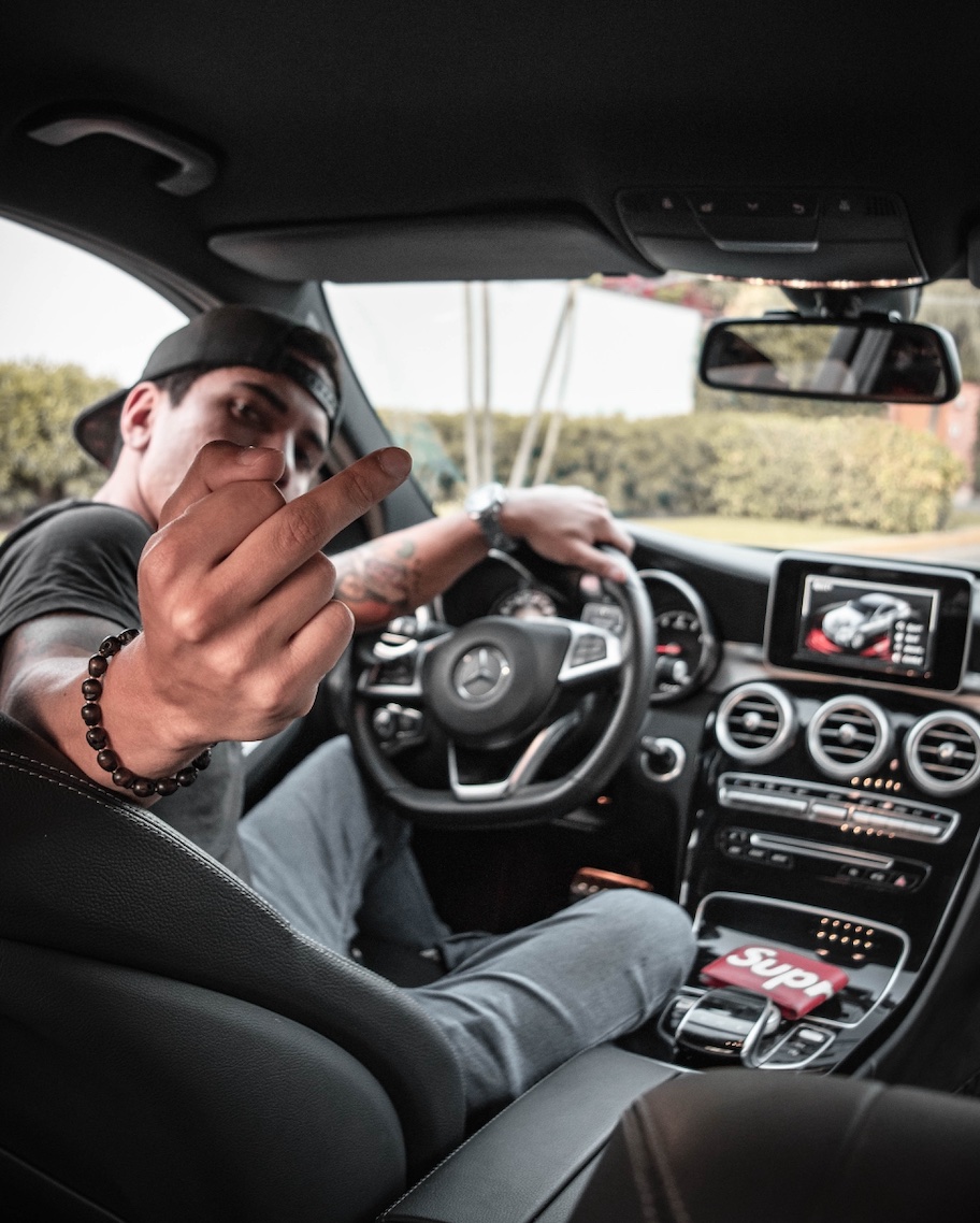 Man in car showing middle finger; image by Jose Carbajal, via Unsplash.com.