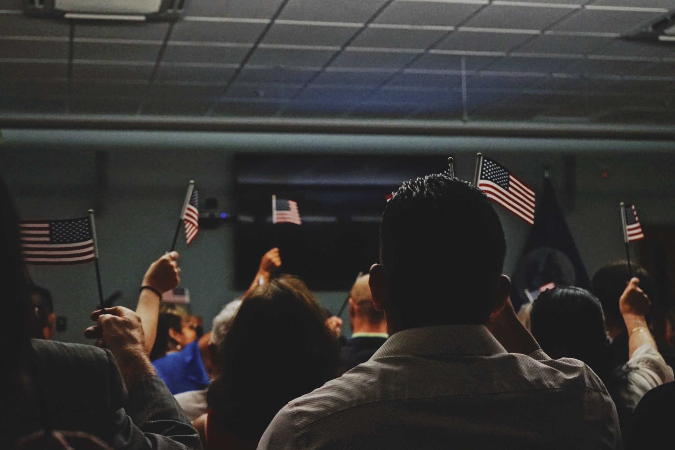 Room full of people waving mini American flags; image by Kerwin Elias, via Unsplash.com