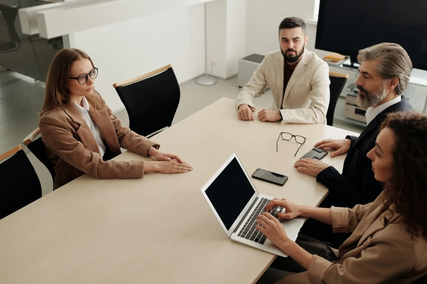 Two men and two women sitting at table in meeting; image by Edmond Dantès, via Pexels.com.