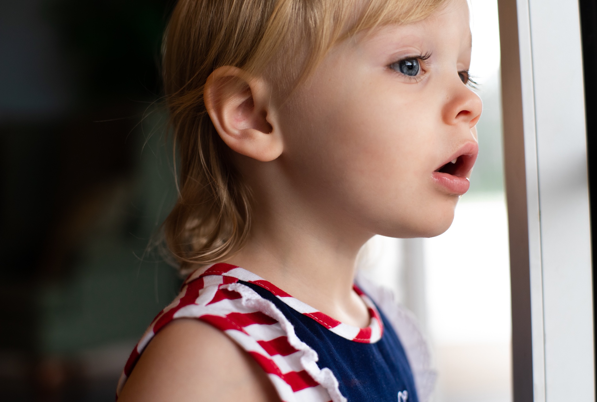 Little blond girl looking out window expectantly; image by Jeremiah Lawrence, via Unsplash.com.