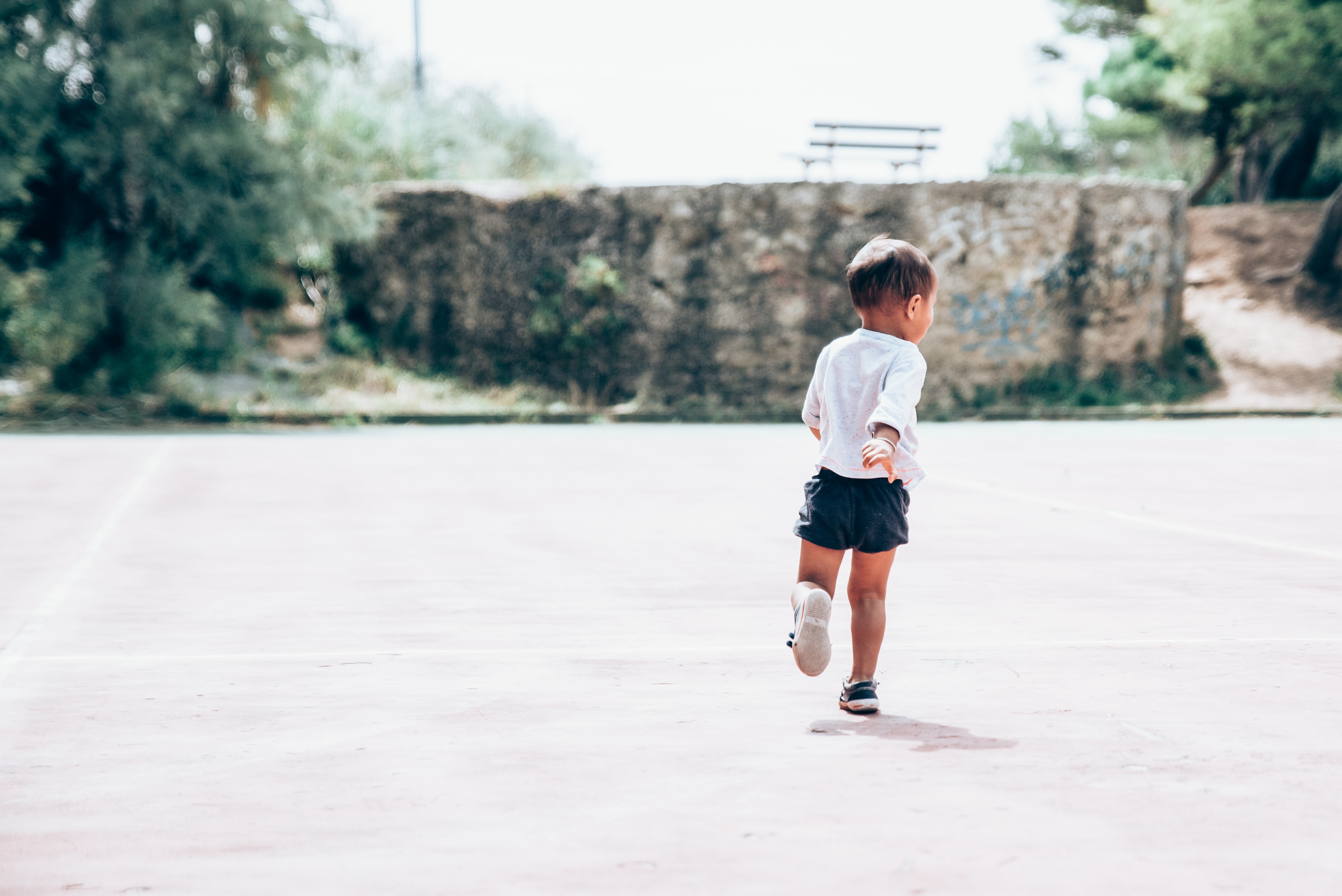 Little boy running from camera in empty partking lot; image by Guillaume de Germain, via Unsplash.com.