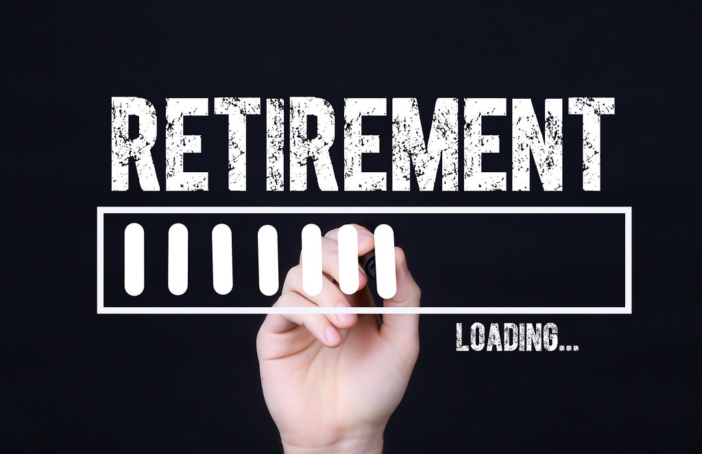A disembodied hand draws a "loading" bar against a dark background, with the word "Retirement" above.