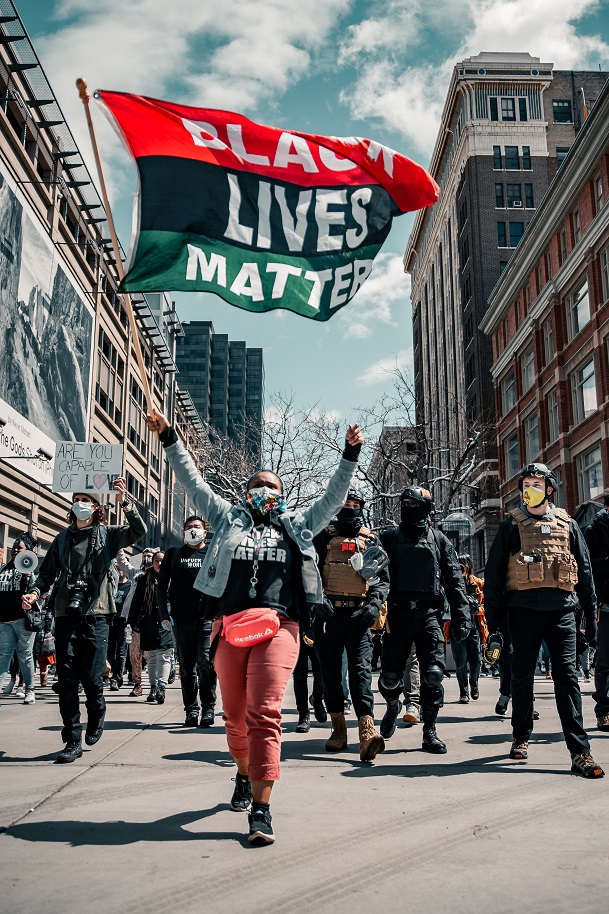 Marchers wave a "Black Lives Matter" banner as police officers look on.