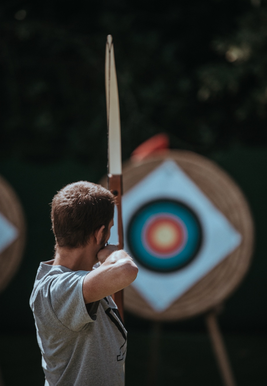 Man with bow taking aim at target; image by Annie Spratt, via Unsplash.com.