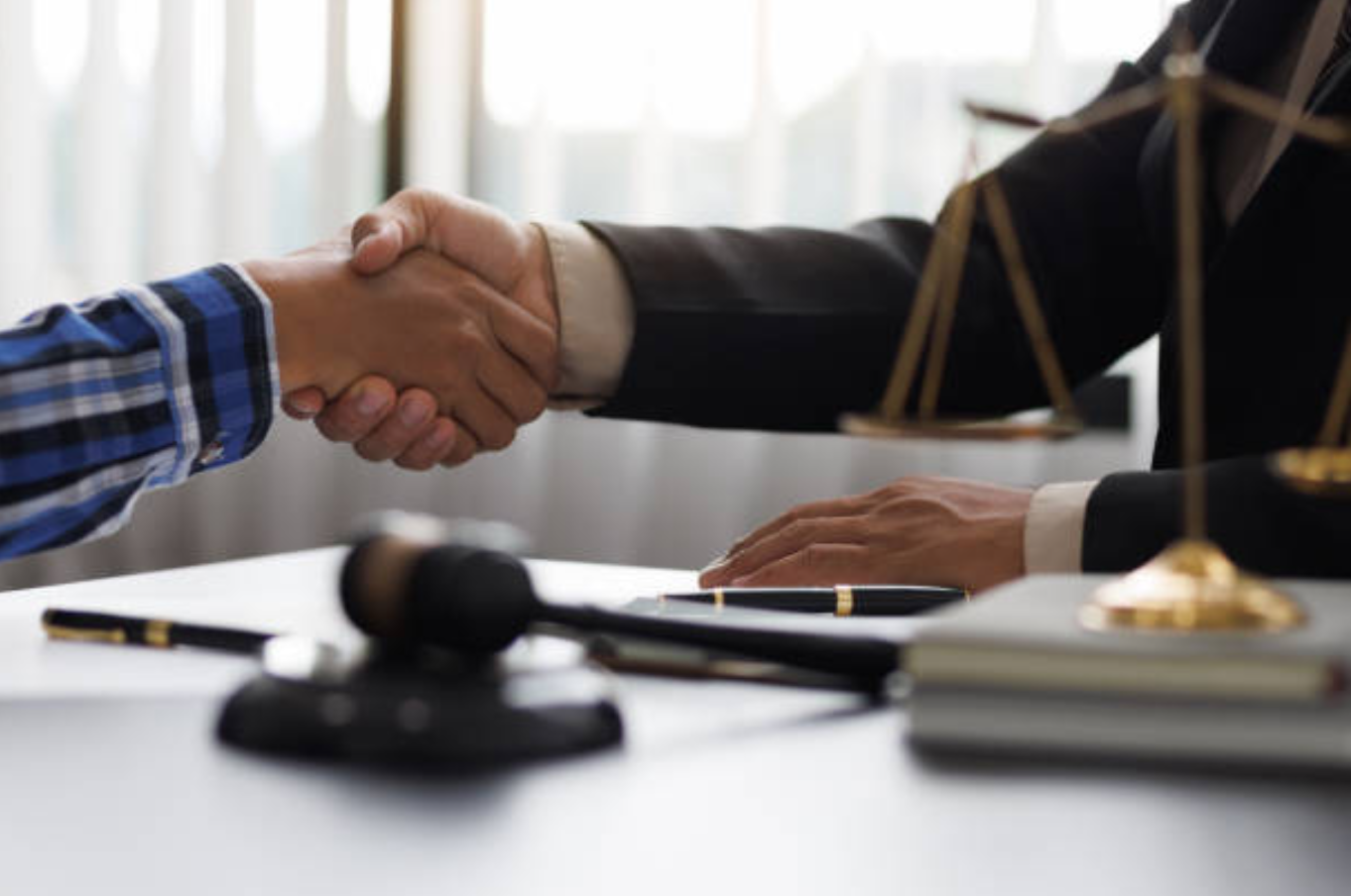 Lawyer shaking hands with client across desk; image by Wasan Tita, via iStockphoto.com.