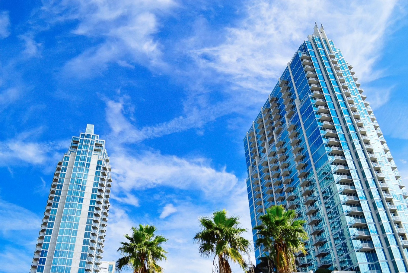 Palm trees by high-rise building; image by Chalo Garcia, via Unsplash.com.